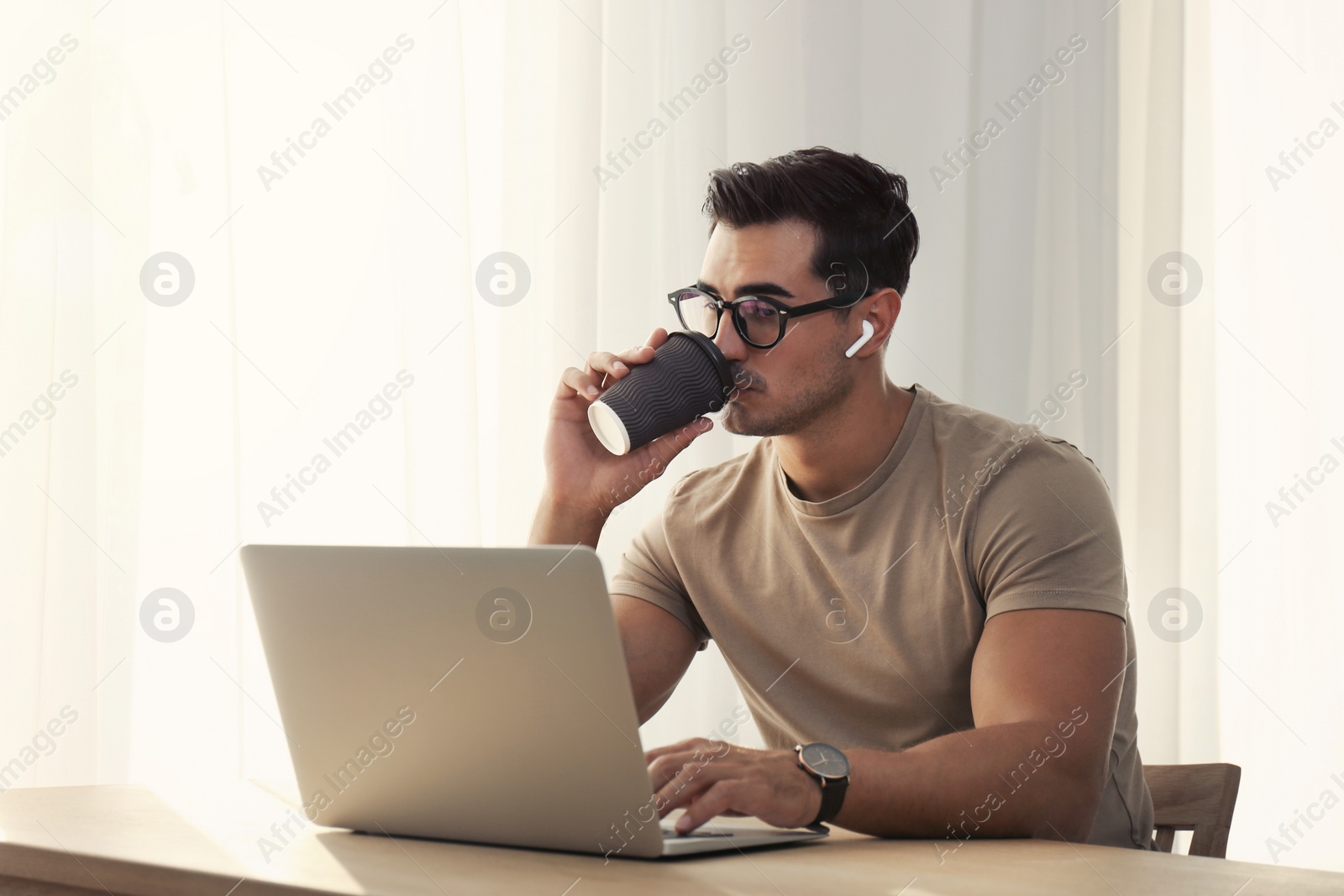 Photo of Portrait of young man with laptop at table indoors