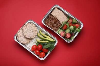 Containers with different fresh food on red background, flat lay