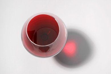 Red wine in glass and shadow on white background, top view. Space for text