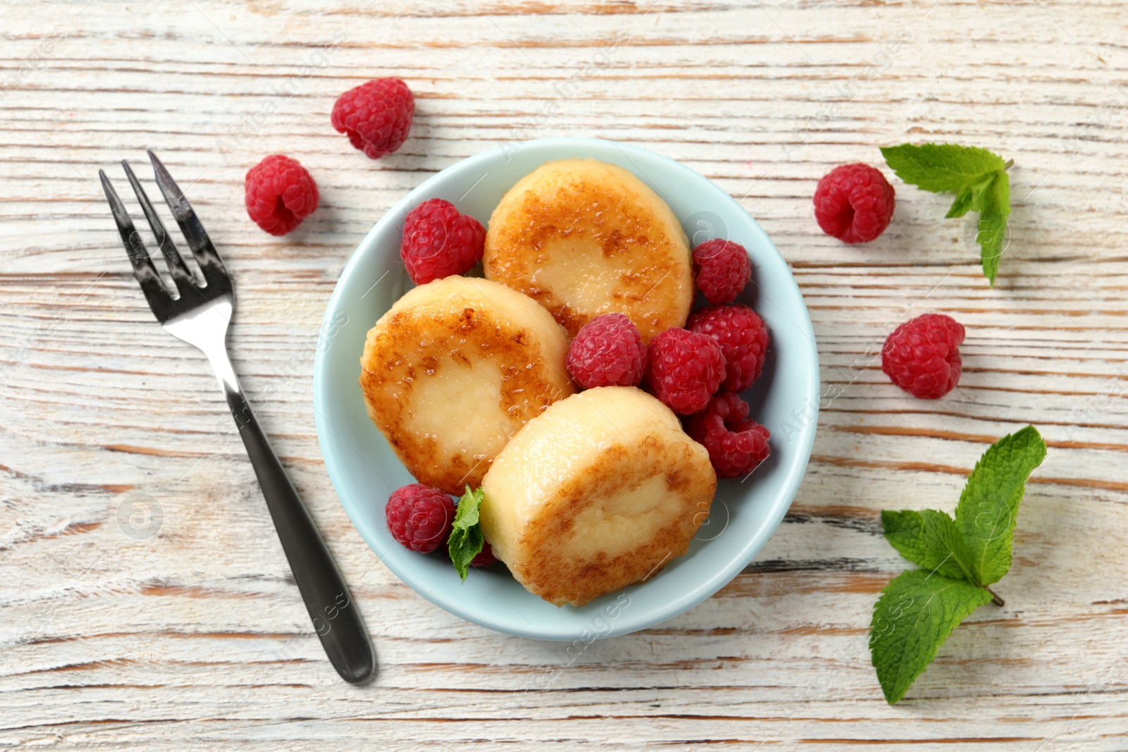 Photo of Delicious cottage cheese pancakes with raspberries and mint on white wooden table, flat lay