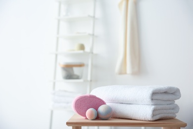 Photo of Clean towels and toiletries on table against blurred background