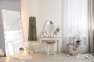 Photo of Large mirror with light bulbs and dressing table in stylish room. Interior design