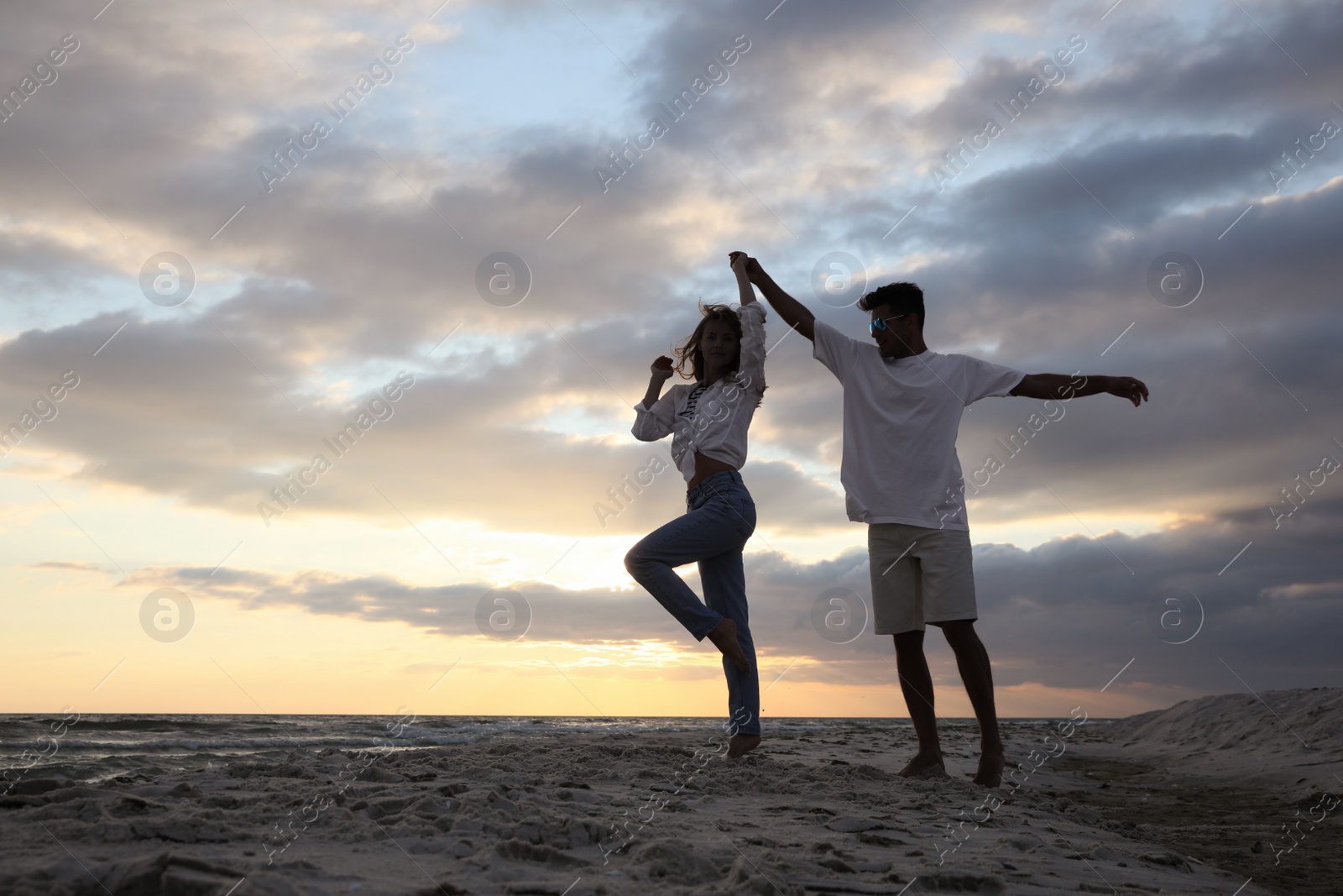 Photo of Happy couple dancing on beach at sunset