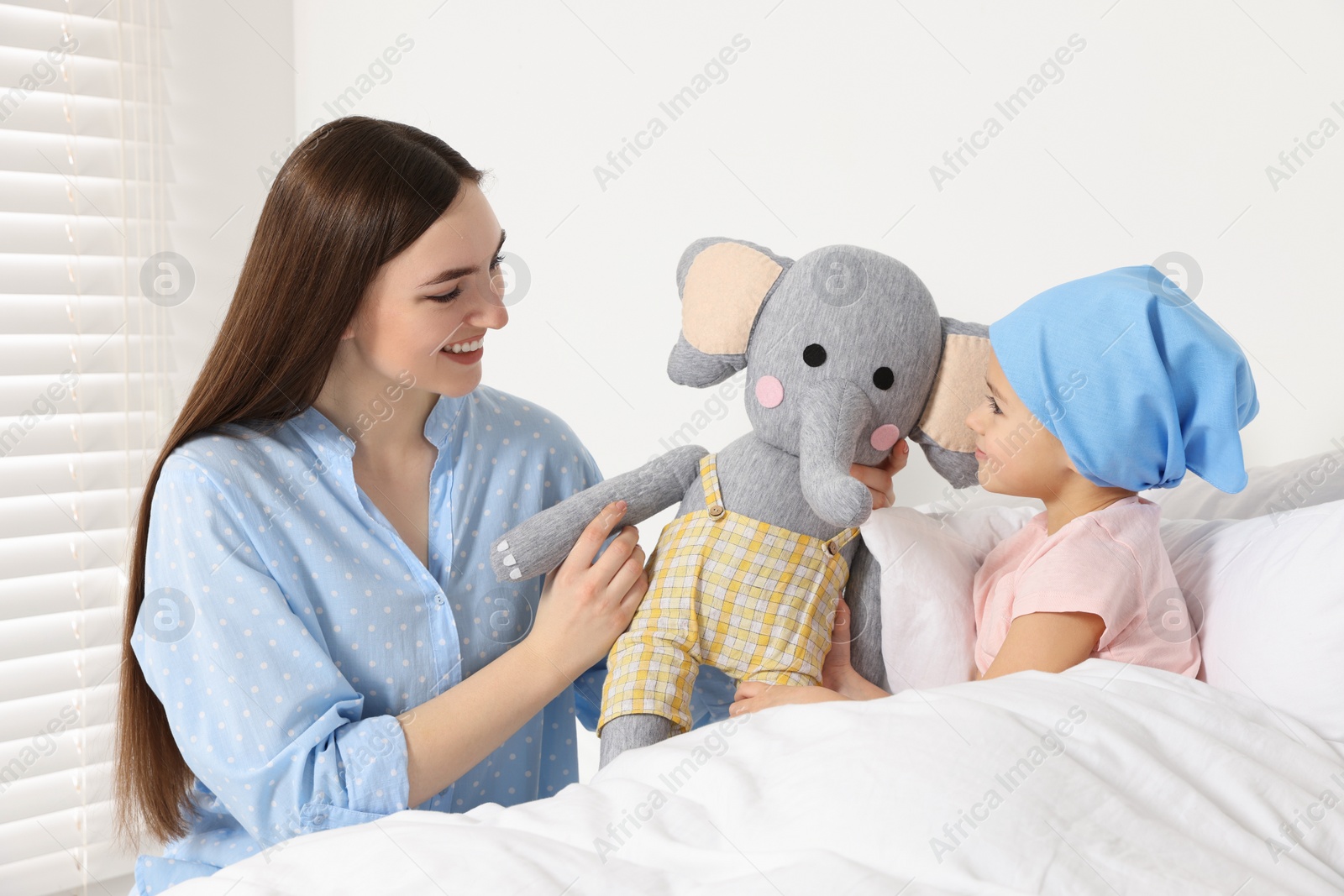 Photo of Childhood cancer. Mother and daughter with toy elephant in hospital