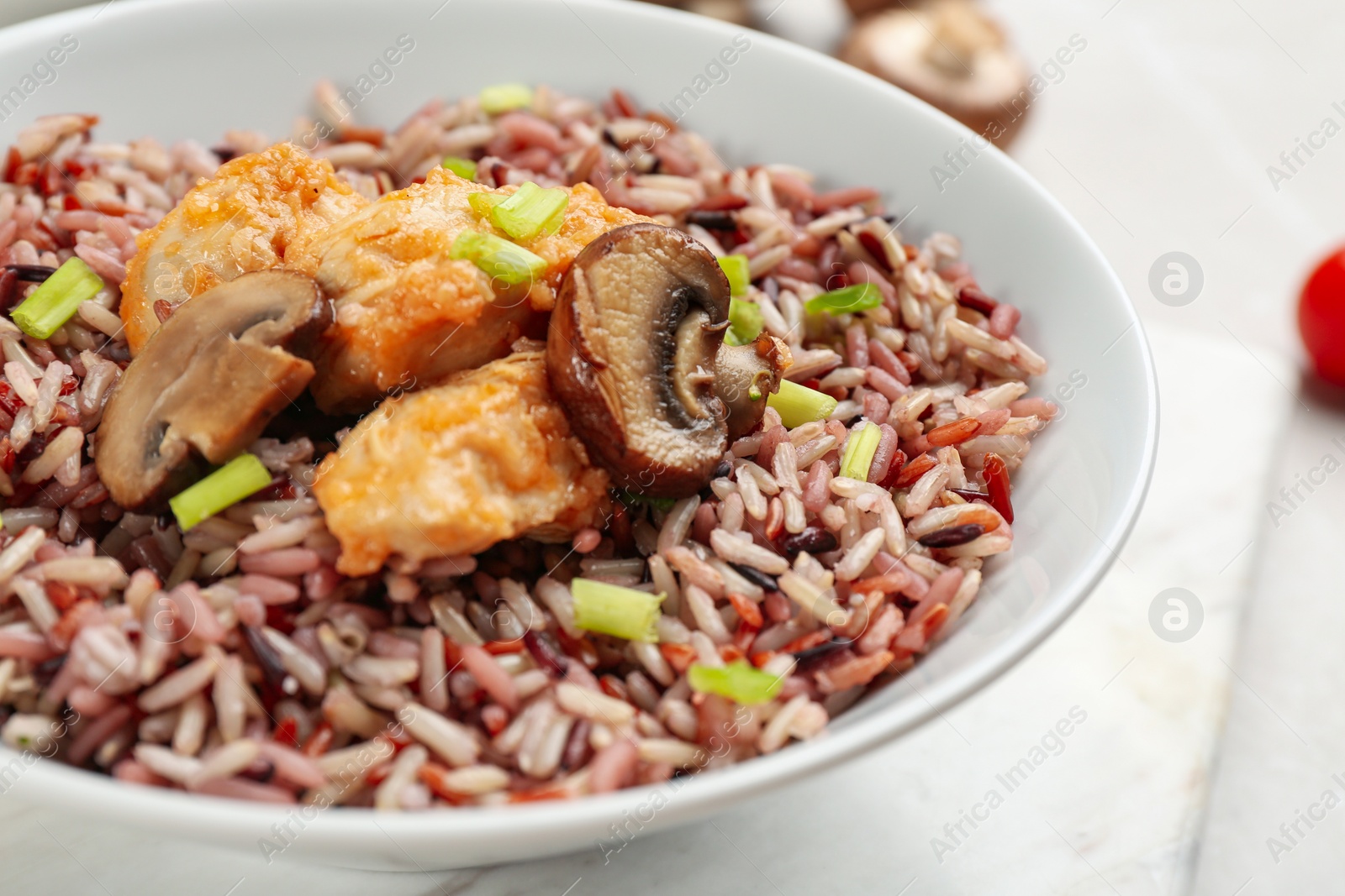 Photo of Tasty brown rice with chicken and mushrooms on table, closeup