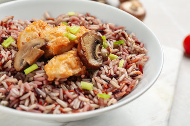 Photo of Tasty brown rice with chicken and mushrooms on table, closeup