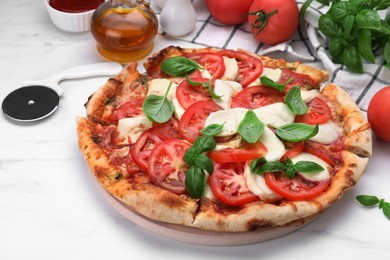 Photo of Delicious Caprese pizza with tomatoes, mozzarella and basil served on white marble table, closeup