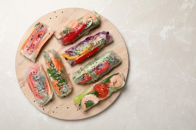 Photo of Delicious rolls wrapped in rice paper on light table, top view. Space for text