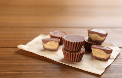 Photo of Delicious peanut butter cups on wooden table, space for text