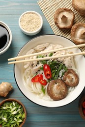 Delicious ramen with meat and ingredients on light blue wooden table, flat lay. Noodle soup