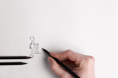 Photo of Woman drawing stairs with pencil to help human figure walking up on white background, top view