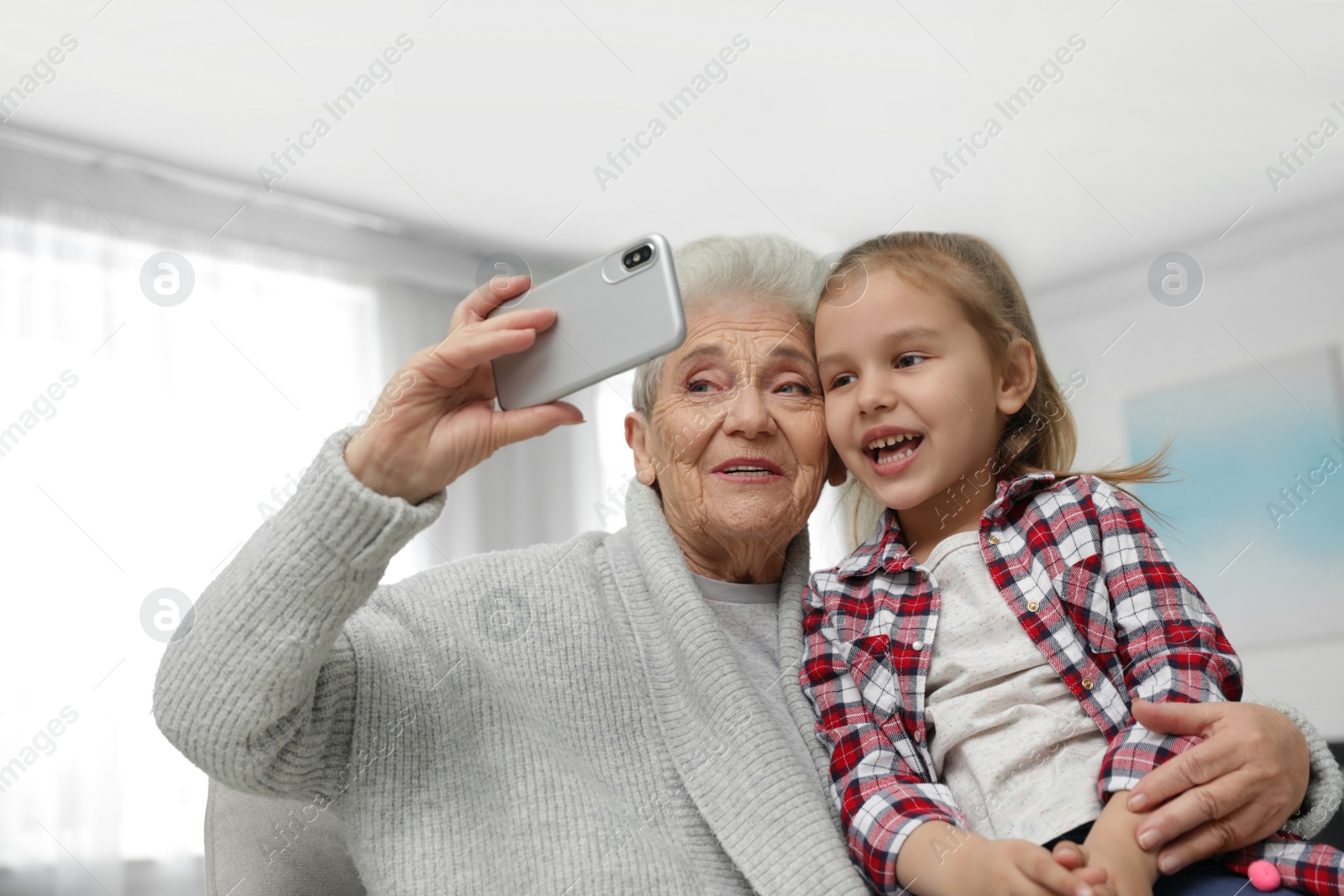 Photo of Cute girl and her grandmother taking selfie  at home