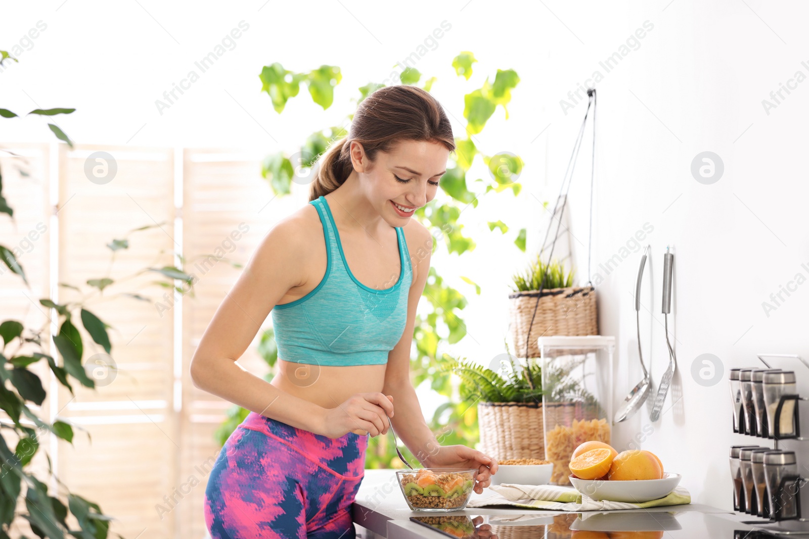 Photo of Young woman in fitness clothes having healthy breakfast at home