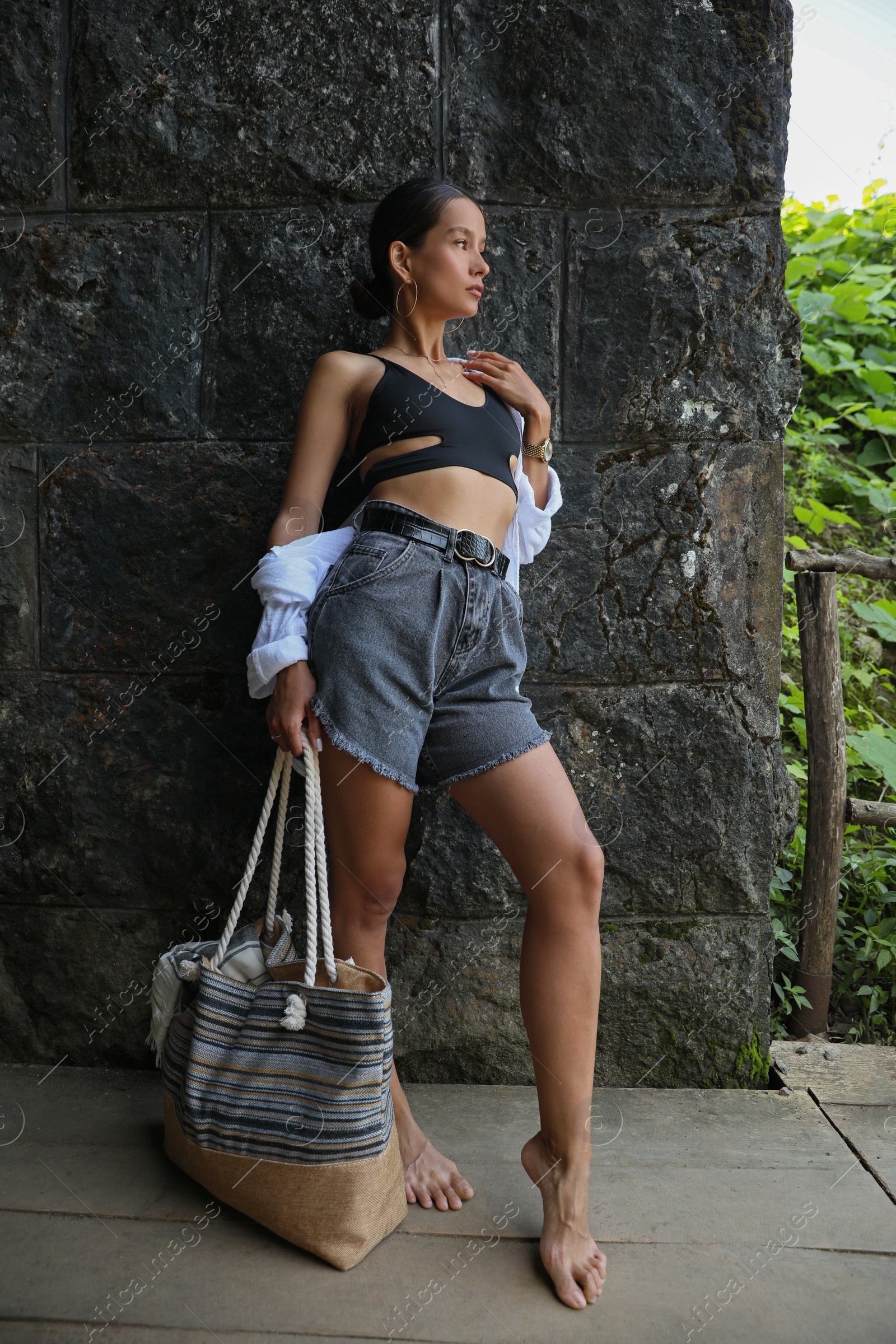 Photo of Beautiful young woman near stone wall outdoors