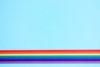 Bright rainbow ribbon on color background, top view with space for text. Symbol of gay community