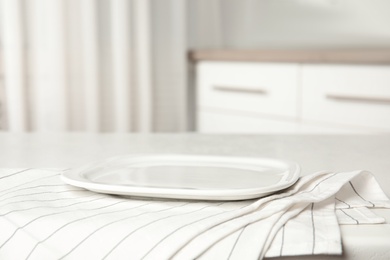 Photo of Empty plate and napkin on white table indoors