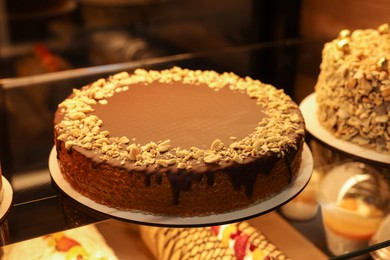 Photo of Delicious wafer cake with condensed milk, chocolate and nuts on counter in bakery shop, closeup