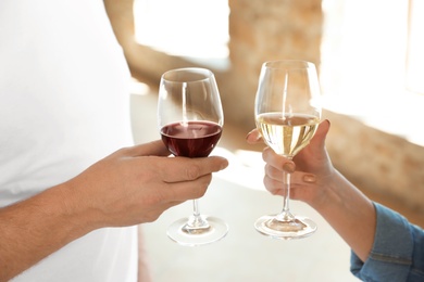 Photo of Couple with glasses of white and red wines indoors, closeup