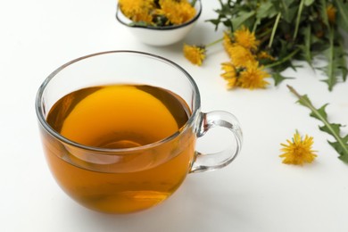 Delicious fresh tea and beautiful dandelion flowers on white background