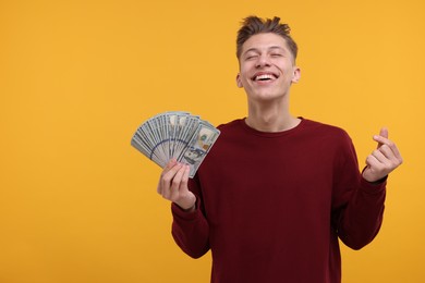 Photo of Happy man with dollar banknotes showing money gesture on yellow background. Space for text