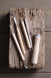 Set of different clay crafting tools on wooden table, top view