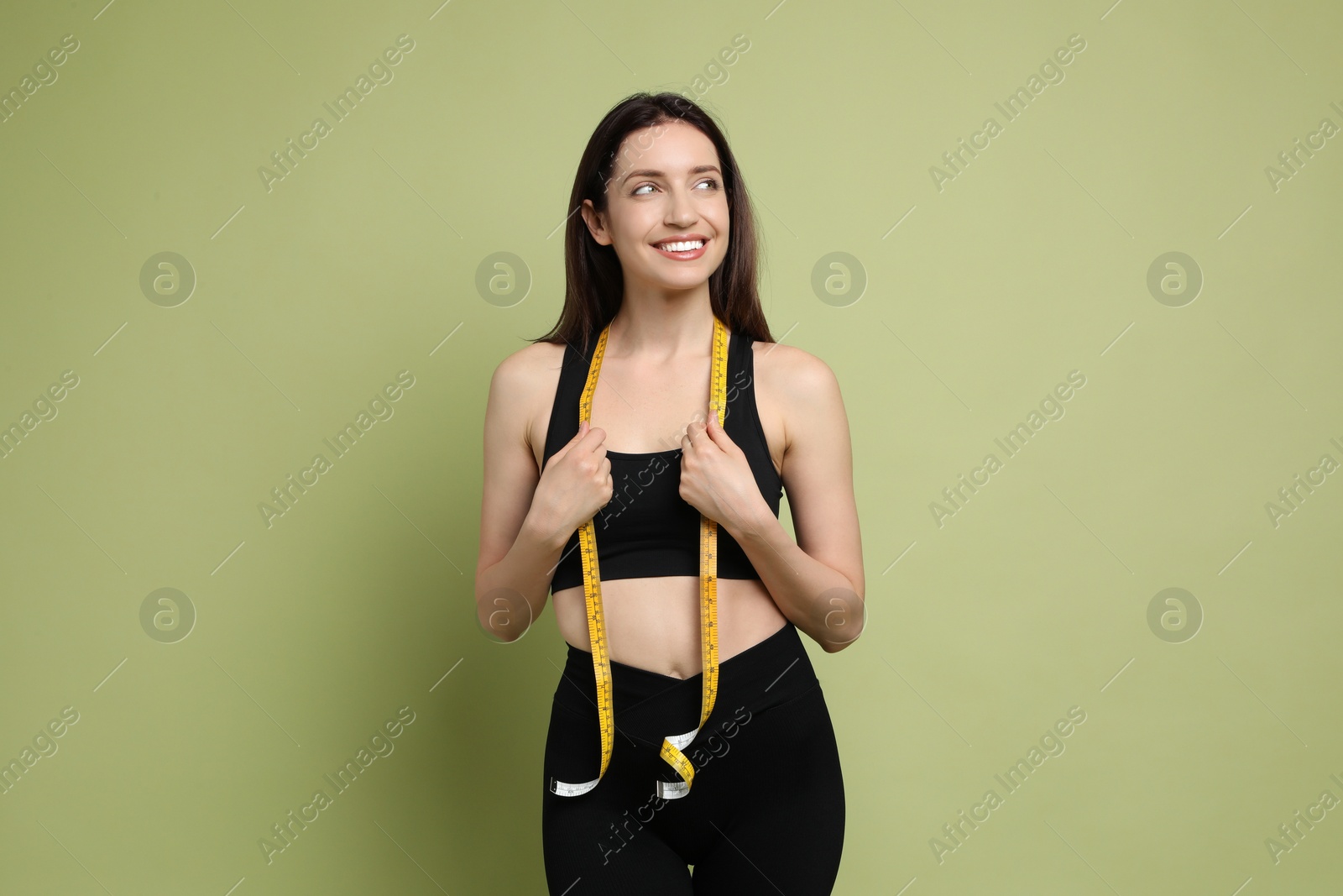 Photo of Happy young woman with measuring tape showing her slim body on green background