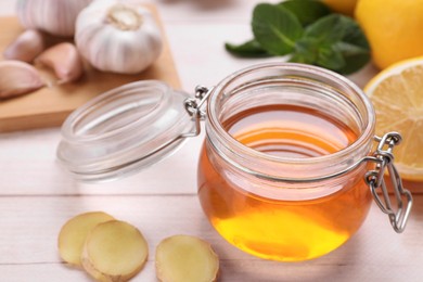 Photo of Natural cough remedies. Jar with honey and ginger on white table, closeup