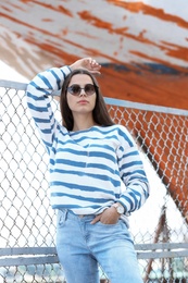 Photo of Young hipster woman in stylish jeans on pier