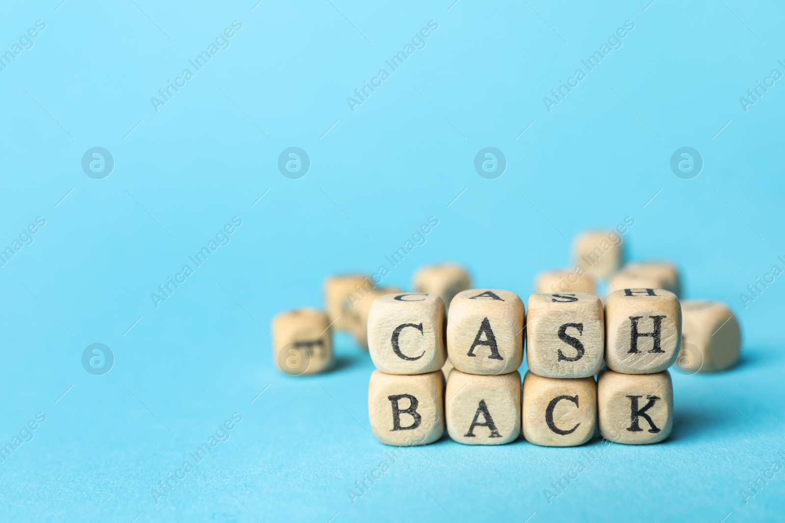 Photo of Word Cashback made with cubes on light blue background, closeup. Space for text