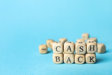 Photo of Word Cashback made with cubes on light blue background, closeup. Space for text