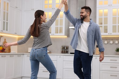 Happy lovely couple dancing together in kitchen