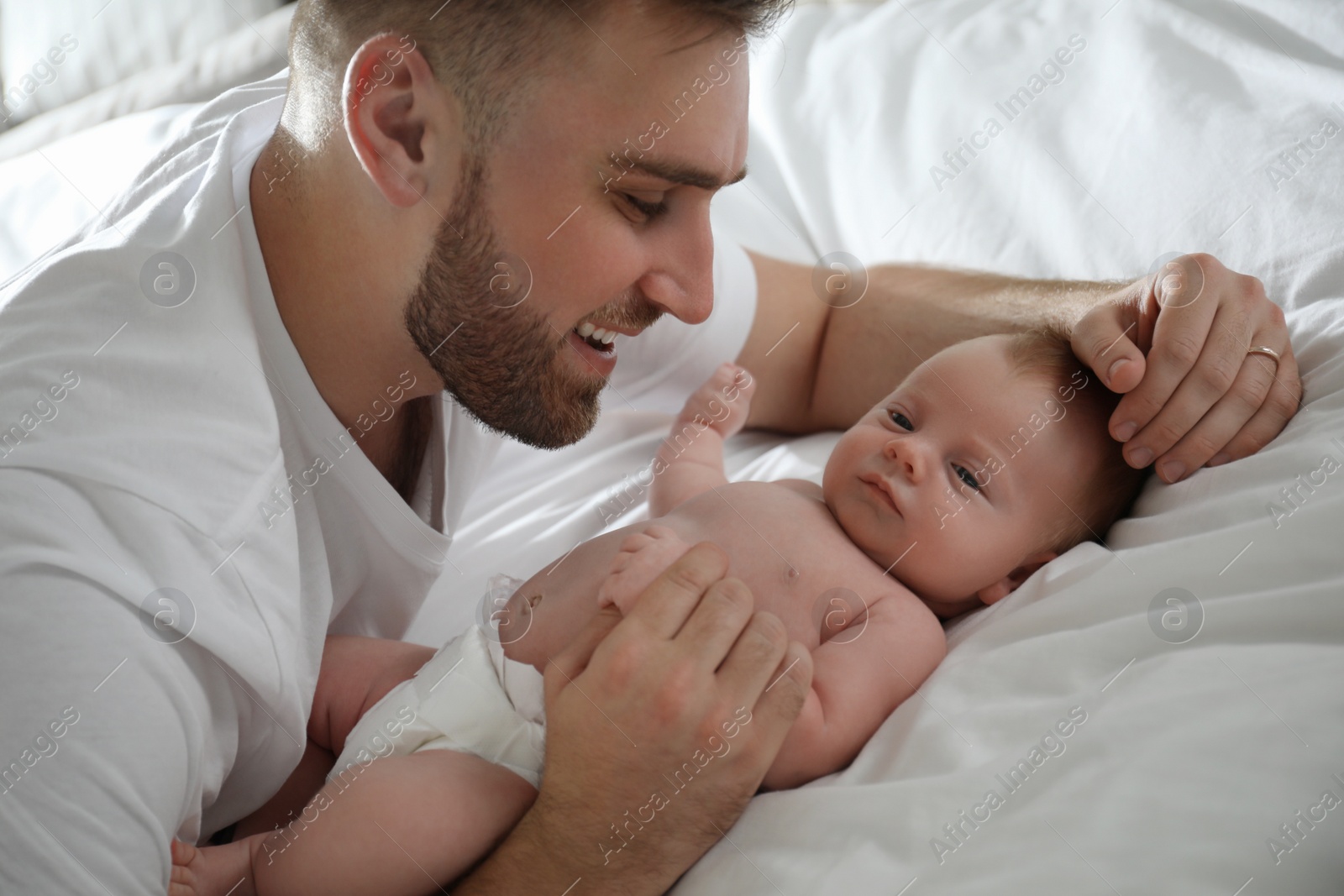 Photo of Father with his newborn son on bed