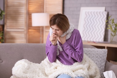 Sick woman with cough suffering from cold on sofa at home