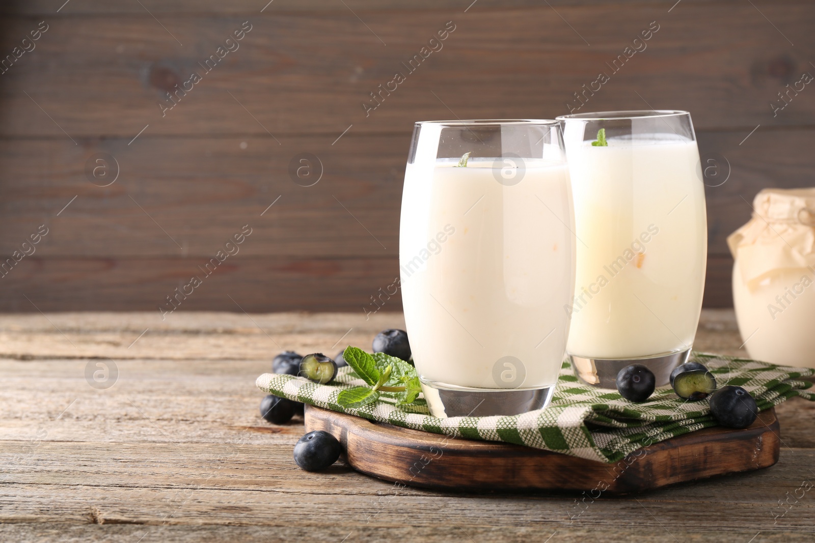 Photo of Tasty yogurt in glasses and blueberries on wooden table. Space for text