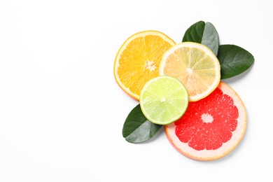 Photo of Slices of fresh ripe citrus fruits and green leaves on white background, flat lay. Space for text