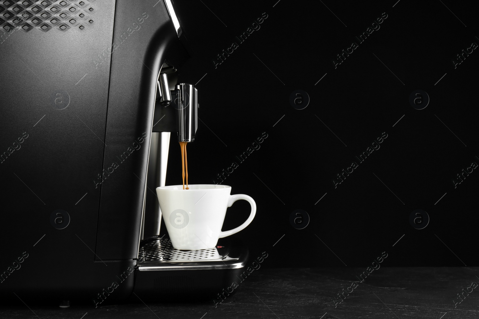 Photo of Making coffee with modern espresso machine on grey table against black background. Space for text