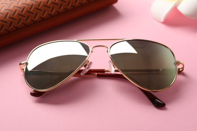 Stylish elegant sunglasses on pink background, closeup