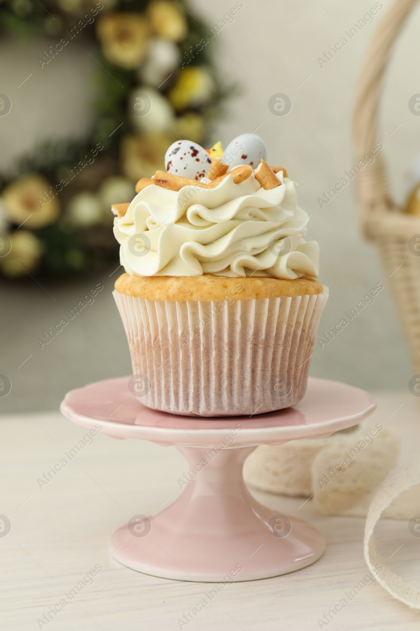 Photo of Tasty Easter cupcake with vanilla cream on light wooden table