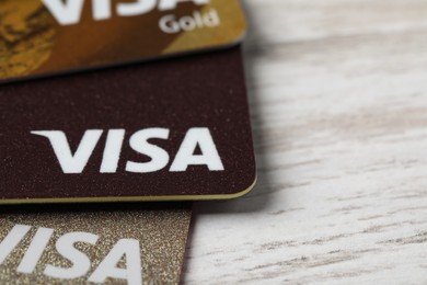 Photo of MYKOLAIV, UKRAINE - FEBRUARY 22, 2022: Visa credit cards on white wooden table, closeup. Space for text