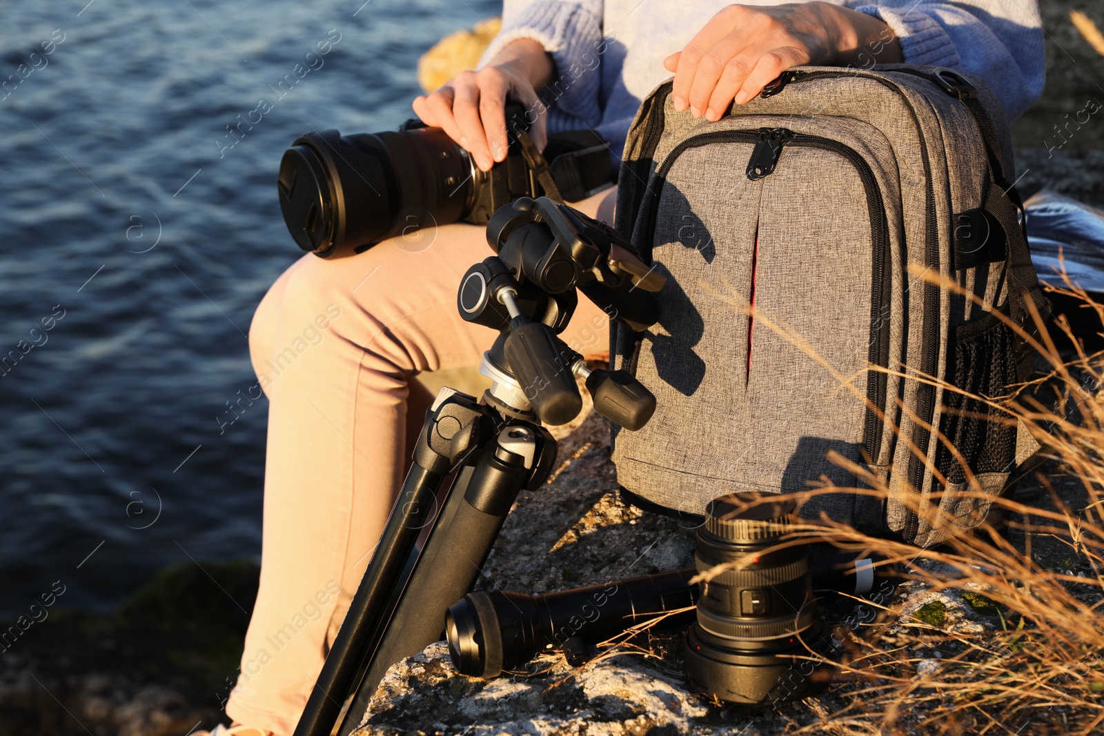 Photo of Photographer with professional equipment on rocky river coast, closeup