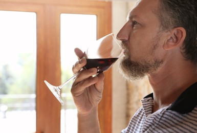Man with glass of red wine indoors