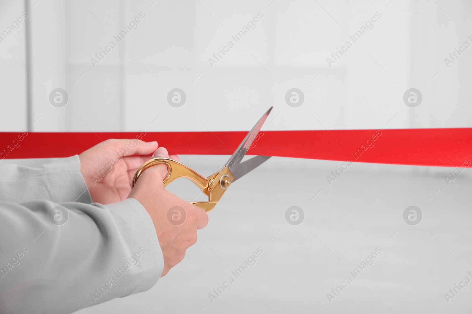 Photo of Man cutting red ribbon on blurred background. Festive ceremony