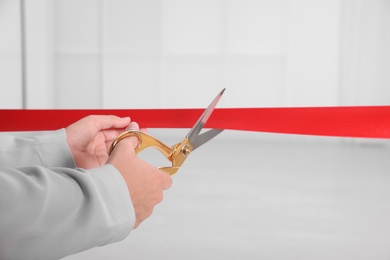 Photo of Man cutting red ribbon on blurred background. Festive ceremony