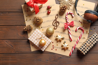 Photo of Flat lay composition with Christmas decorations, music sheets and headphones on wooden background