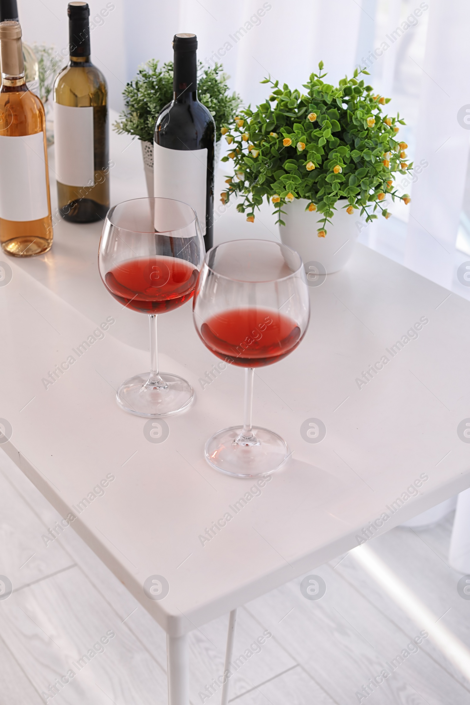 Photo of Glasses and bottles with delicious wine on table indoors