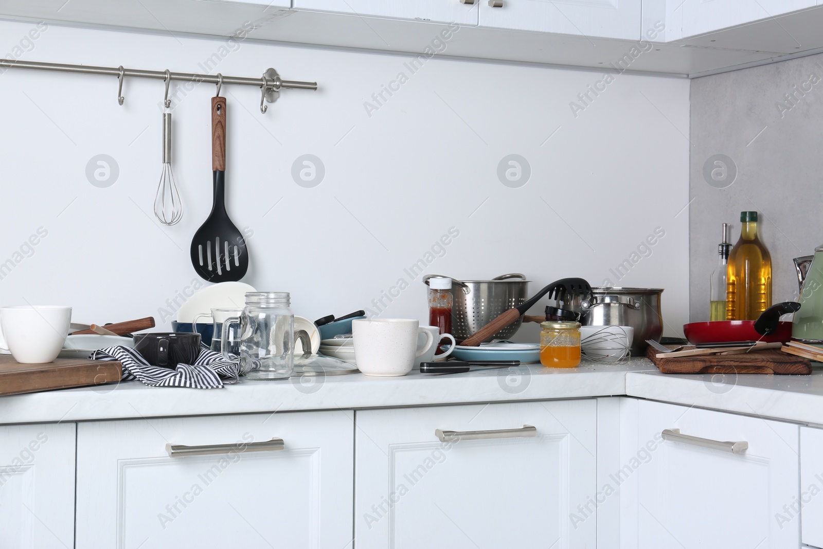 Photo of Many dirty utensils and dishware on countertop in messy kitchen