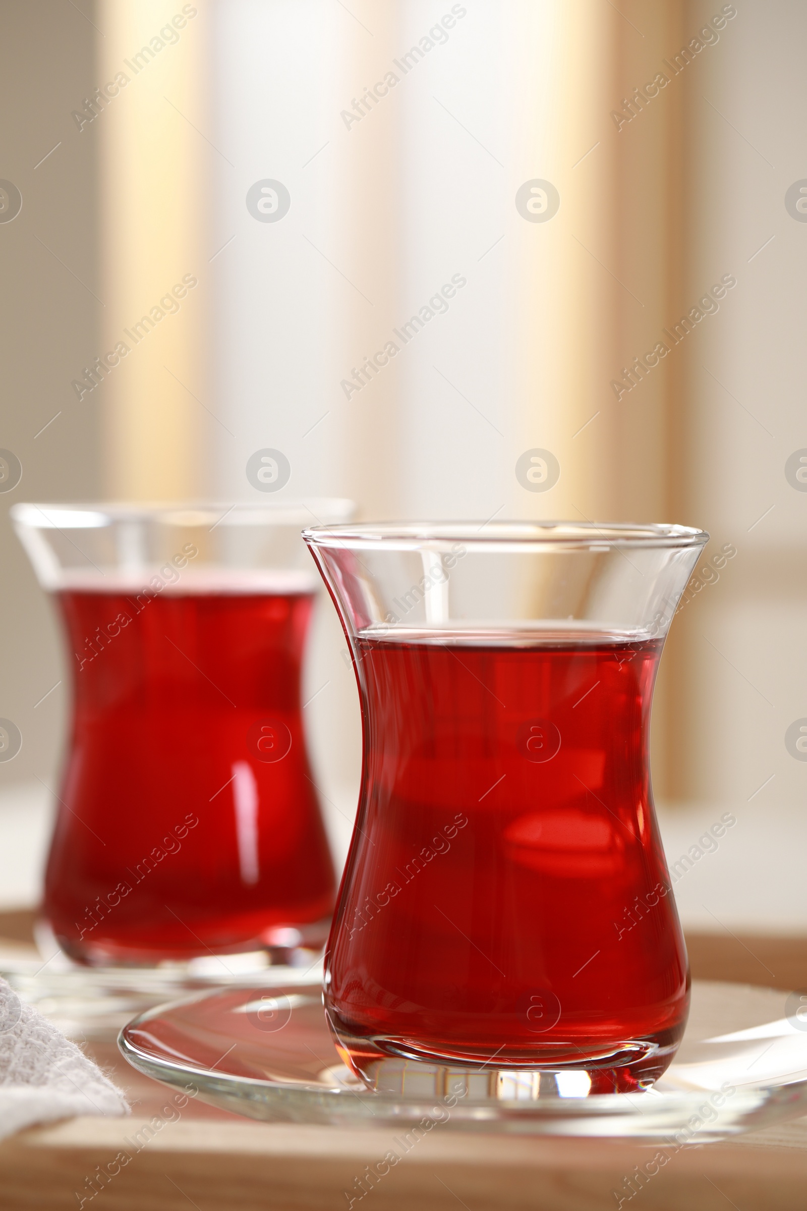 Photo of Glasses of traditional Turkish tea on wooden tray indoors