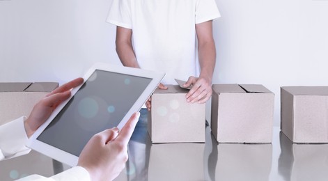 Image of Production line. Manager using tablet while worker folding cardboard boxes, closeup