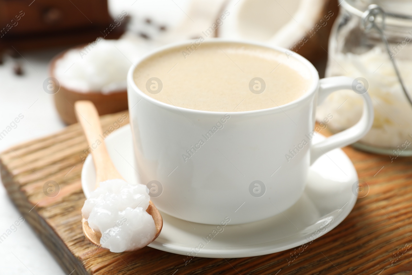 Photo of Delicious coffee with organic coconut oil on wooden board