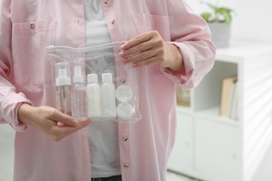 Woman holding plastic bag of cosmetic travel kit indoors, closeup and space for text. Bath accessories